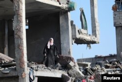 A Palestinian woman stands inside a destroyed building in Nuseirat, central Gaza Strip, after Israeli forces withdrew from parts of Nuseirat after a ground operations, Nov. 29, 2024.