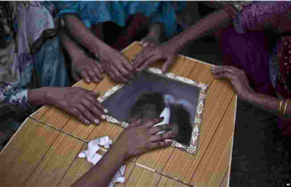 Pokistonlik ayollar portlashda halok bo'lgan qarindoshining tobutiga qo'l tekkizmoqda, 22-sentabr, 2013-yil.