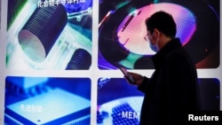 Seorang pengunjung memperhatikan perangkat semikonduktor dalam pameran Semicon China di Shanghai, China, 17 Maret 2021. (Foto: Aly Song/Reuters)