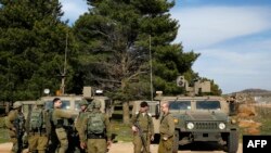 Des soldats israéliens se rassemblent sur les hauteurs du Golan annexées par Israël à la frontière avec la Syrie le 27 février 2020, après qu'un drone israélien aurait percuté un véhicule dans le village syrien de Hader (Quneitra), au bord du plateau de Golan. AFP/ JALAA MAREY