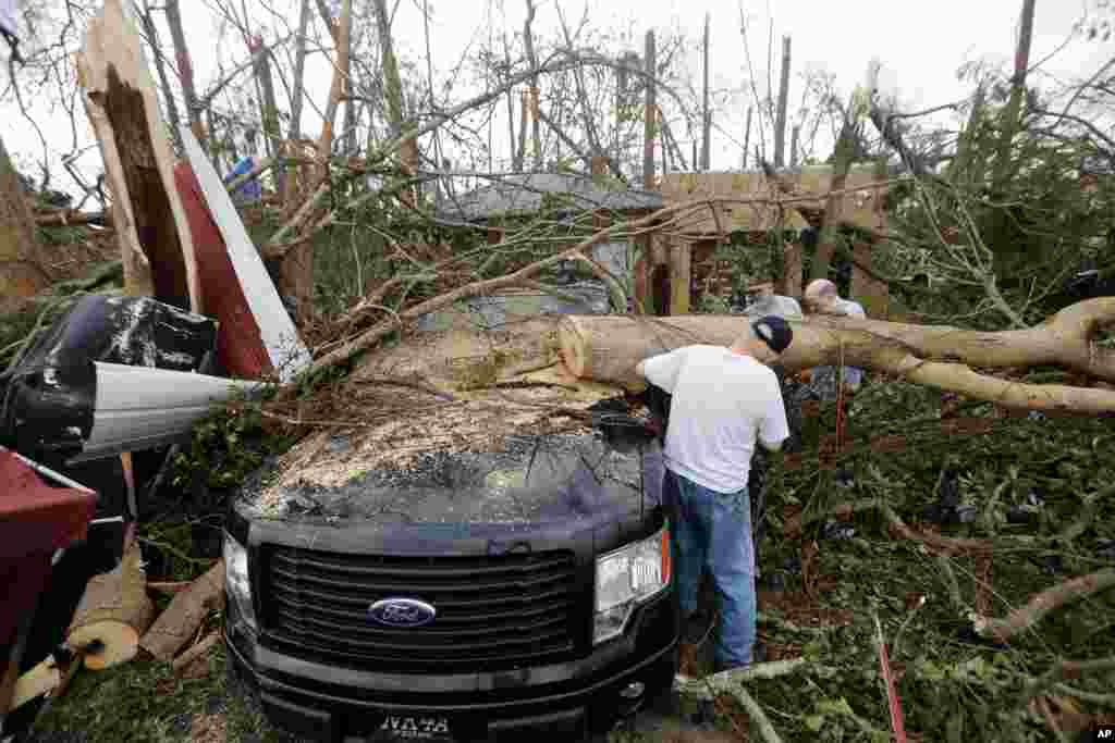 People cut away a tree that'll on a vehicle in the aftermath of Hurricane Michael in Panama City, Fla., Thursday, Oct. 11, 2018. (AP Photo/Gerald Herbert)