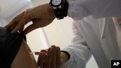 FILE - A doctor injects vaccine into a patient's arm, in Rome, Italy, Feb. 23, 2018.