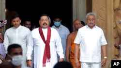 Sri Lanka’s former President Mahinda Rajapaksa, center, leaves with his younger brother, President Gotabaya Rajapaksa, right, after being sworn in as the prime minister at Kelaniya Royal Buddhist temple in Colombo, Sri Lanka, Sunday, Aug. 9, 2020. …