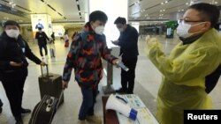 中國浙江省杭州市火車站一名旅客使用手機中的綠色健康碼向車站檢疫人員顯示他的健康狀況。（2020年2月17日） 