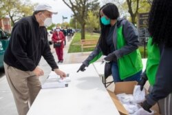 New York City Department of Parks & Recreation staff distribute free face masks at the Mauro playground in the Kew Gardens Hills neighborhood of the Queens borough of New York, May 5, 2020.
