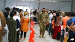 FILE - Afghan refugees line up for food in a dining hall at Fort Bliss' Doña Ana Village where they are being housed in Chaparral, N.M., Sept. 10, 2021.