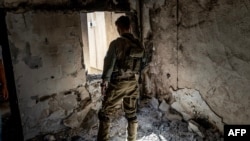 An Israeli soldier stands inside a house burned down during the October 7 attack in Kibbutz Kfar Aza, close to the southern Israeli border with the Gaza Strip on November 8, 2023, amid ongoing battles between Israel and the Palestinian Hamas group. (Photo by FADEL SENNA / AFP)