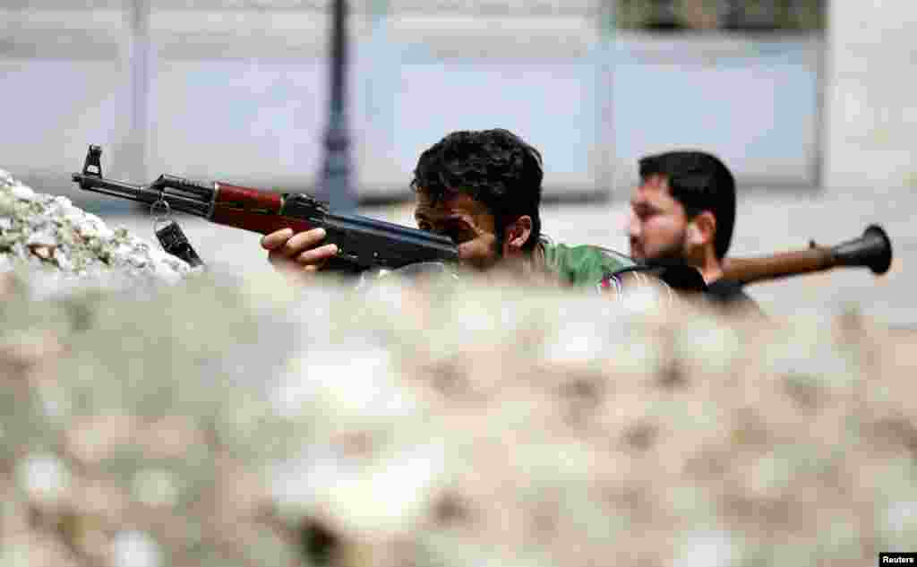 &Ouml;zg&uuml;r Suriye Ordusundan askerler Halep'te sokaklardaki barikatların arkasında siper alırken,13 Ağustos 2012