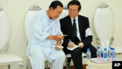 លោកនាយករដ្ឋមន្ត្រី ហ៊ុន សែន (ឆ្វេង) និយាយជាមួយនឹងលោក កឹម សុខា មេដឹកនាំគណបក្សសង្គ្រោះជាតិដែលត្រូវបានតុលាការកំពូលរំលាយ ក្នុងពិធីបុណ្យសពម្ដាយក្មេករបស់ លោក ហ៊ុន សែន ក្នុងរាជធានីភ្នំពេញ ថ្ងៃទី៥ ខែឧសភា ឆ្នាំ២០២០។ (Pool via AP)