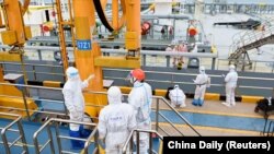 在中國山東省青島港，身著防護衣的海關出入境人員在檢查一艘載有進口原油的​​油輪。 （2022年5月9日）