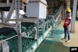 A man watches a conveyor belt loaded with chunks of raw cobalt after a first transformation at a plant in Lubumbashi, Congo, on Feb. 16, 2018, before being exported, mainly to China, to be refined. (Photo by SAMIR TOUNSI / AFP)