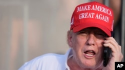 El candidato presidencial republicano, el expresidente Donald Trump, habla por teléfono mientras observa el juego en la ronda final de LIV Golf Miami, en el Trump National Doral Golf Club, el domingo 7 de abril de 2024, en Doral, EEUU.