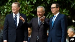 Chinese Vice Premier Liu He, center, flanked by U.S. Trade Representative Robert Lighthizer, left, and Treasury Secretary Steven Mnuchin, gestures to the media before a ministerial-level trade meeting in Washington, Oct. 10, 2019. 