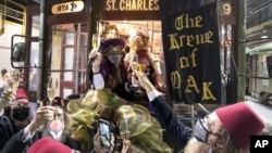 Members of the Krewe of Oak toast Carnival as the Phunny Phorty Phellows start their 40th anniversary streetcar ride in New Orleans, Wednesday, Jan. 6, 2021. (David Grunfeld/The Times-Picayune/The New Orleans Advocate via AP) 