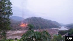 This handout from Kawthoolei Today taken and released on April 27, 2021 shows fires burning at a Myanmar military base along the bank of the Salween river, as seen from Mae Sam Laep town in Thailand's Mae Hong Son province, after the base was attacked and