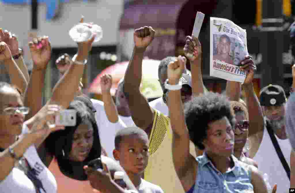 People hold up newspapers and their clinched fists at a gathering to protest the acquittal of George Zimmerman, Newark, New Jersey, July 14, 2013.