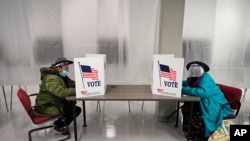 Two voters fill out ballots during early voting at the Cuyahoga County Board of Elections, Oct. 6, 2020, in Cleveland.