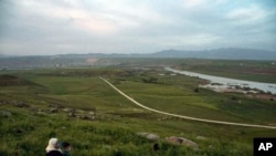 FILE - In this May 1, 2019, photo, a woman and child sit on a hill overlooking the Euphrates River in Derik, Syria. Turkey wants to establish a safe zone east of the Euphrates River in Syria.