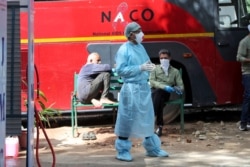 An Indian doctor stand near a disinfectant tunnel outside a hospital where most COVID-19 patients are being treated in Jammu, India, during lockdown in Jammu, India, April.6, 2020.