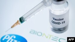 (FILES) In this file photo taken on November 23, 2020 This illustration picture taken on November 23, 2020 shows a bottle reading "Vaccine Covid-19" and a syringe next to the Pfizer and Biontech logo. - Britain on December 2, 2020 became the first country