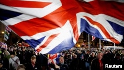 FILE - A man waves a British flag on Brexit day in London, Britain, Jan. 31, 2020.