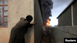 A woman looks at fire and smoke from oil wells set ablaze by Islamic State militants before the fled the oil-producing region of Qayyara, Iraq, Nov. 4, 2016. 